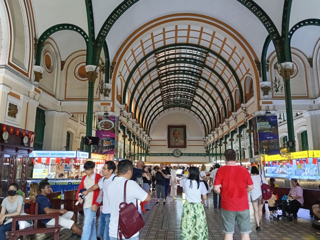 Interior view of the Saigon Central Post Office showcasing its grand architecture, arched ceiling, and people exploring the space.