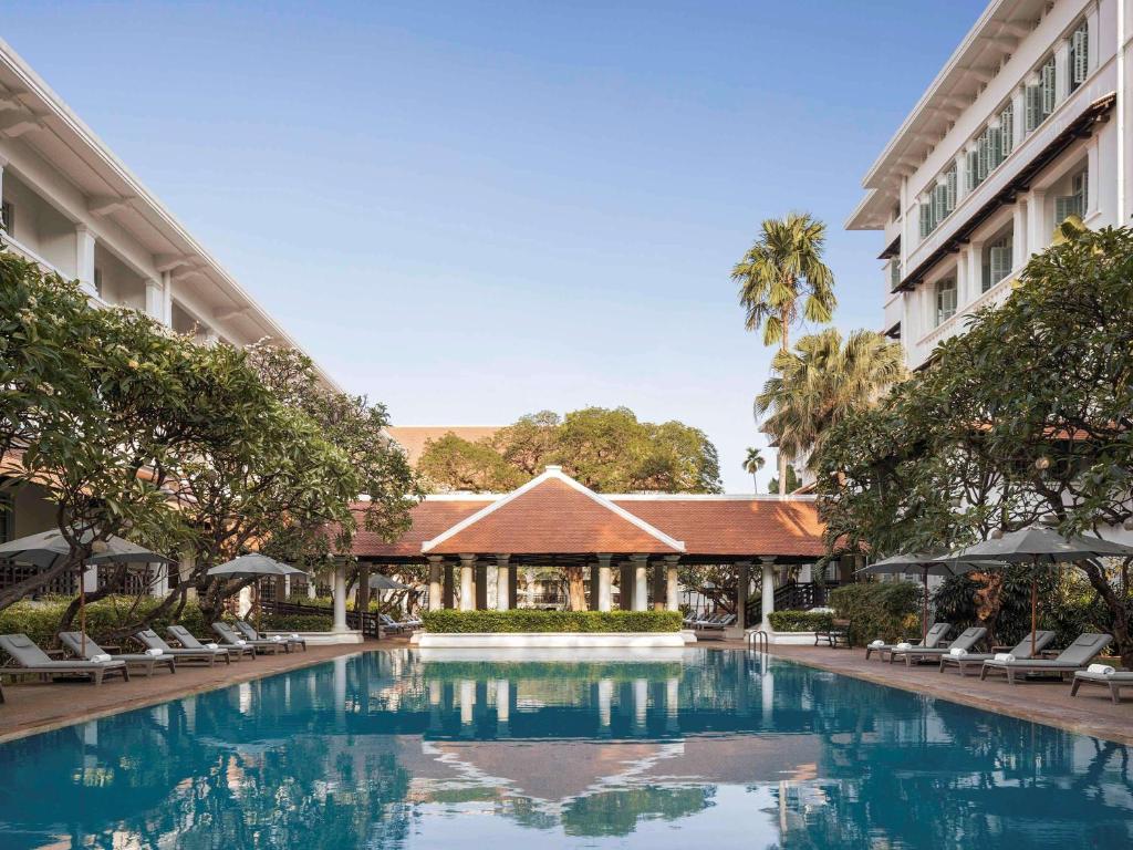 A tranquil pool area surrounded by lush greenery and lounge chairs at a luxury hotel in Phnom Penh, Cambodia.