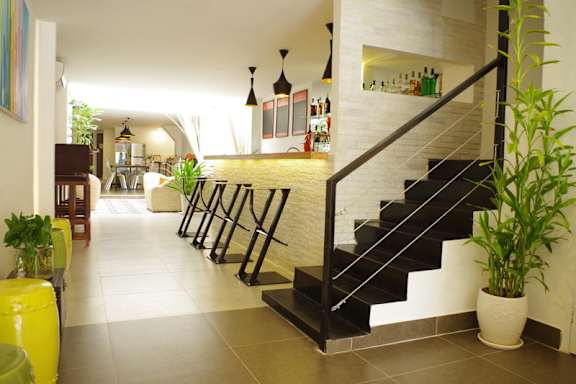 Interior view of a modern hostel with a bar area, seating, and a staircase.
