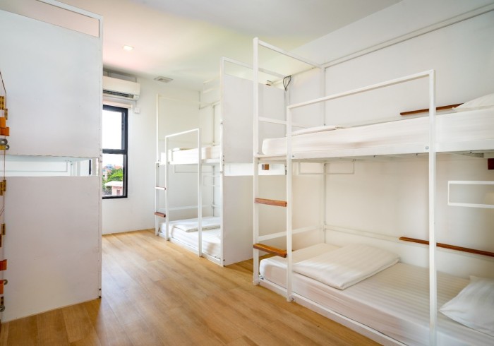 Interior of a modern hostel room featuring bunk beds and wooden flooring.