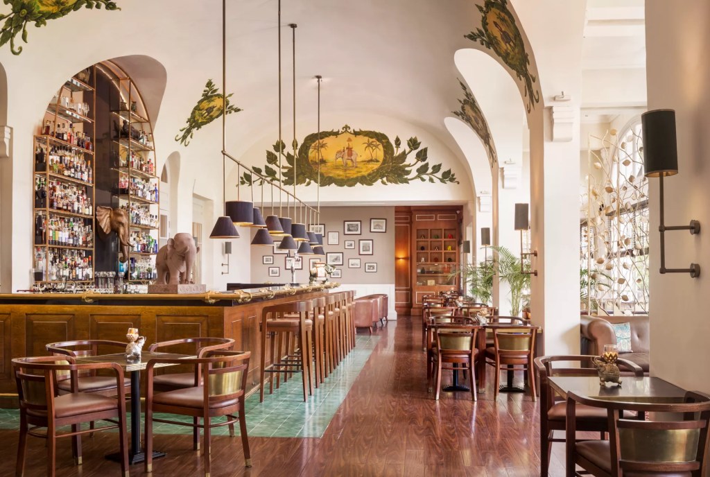 Elegant interior of a luxury hotel bar in Phnom Penh, featuring a wooden bar, decorative ceiling, and stylish seating arrangements.