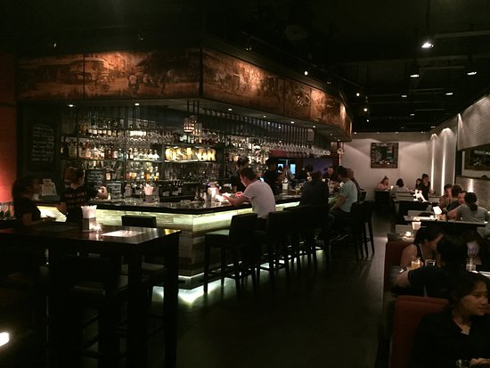 Interior view of Oskar Bistro, showcasing a stylish bar area with patrons enjoying drinks and a cozy atmosphere.