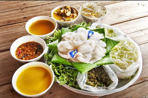 A traditional Cambodian dish featuring rice vermicelli noodles, assorted herbs, fresh vegetables, and a selection of flavorful sauces served in bowls.