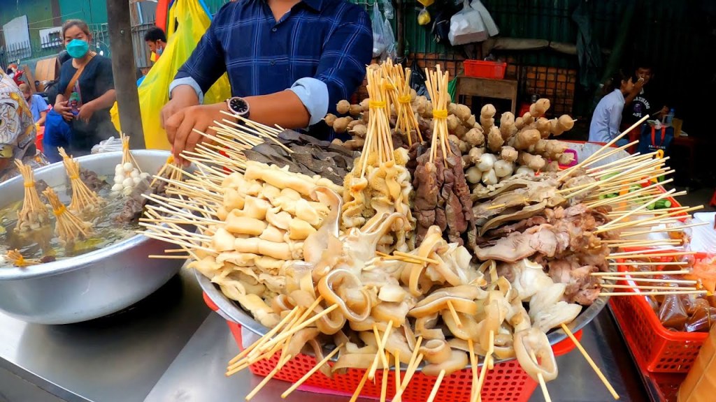 A street food vendor in Phnom Penh, showcasing a variety of skewered meat and seafood ready for cooking.