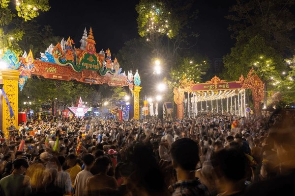Crowd celebrating under illuminated arches at a night festival in Phnom Penh, Cambodia.