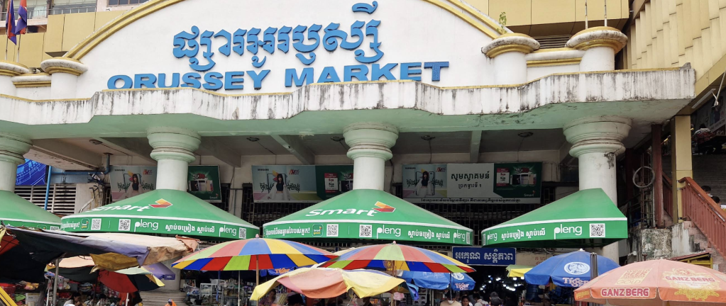 Entrance of Orussey Market in Phnom Penh, featuring colorful umbrellas and signage.
