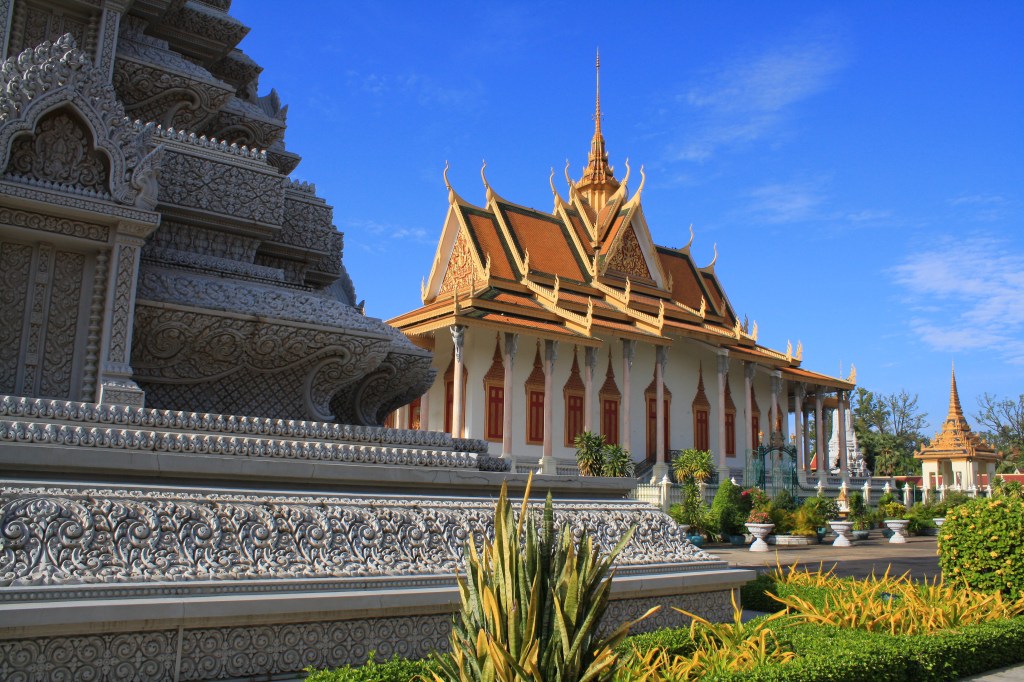 The Royal Palace and Silver Pagoda in Phnom Penh, showcasing intricate architecture and lush gardens under a clear blue sky.