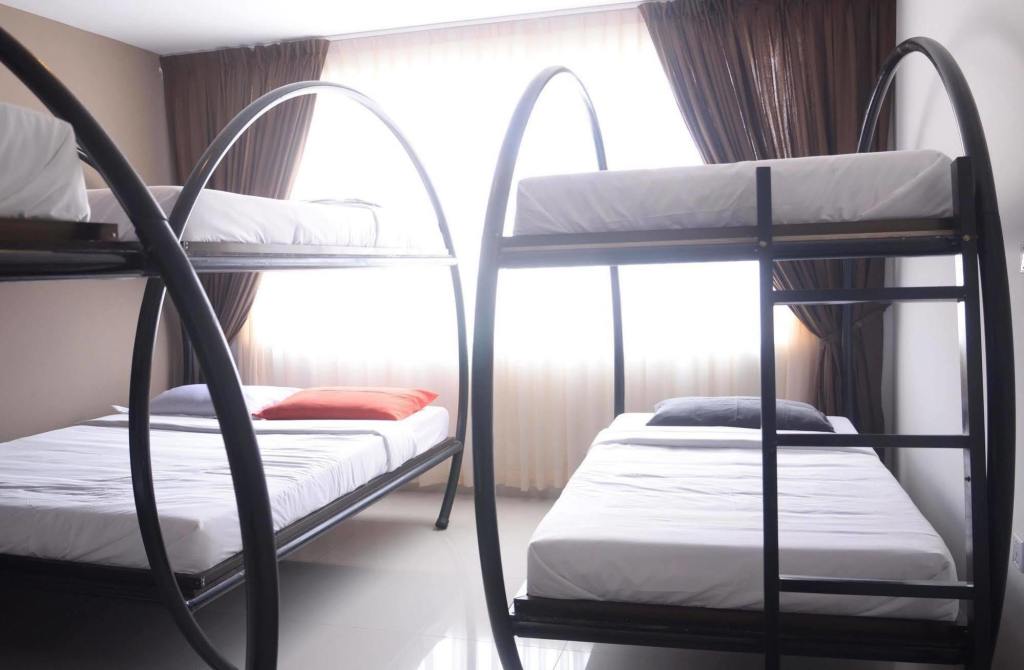 Interior of a hostel room featuring modern bunk beds with clean linens and natural light coming through the window.
