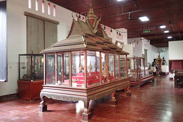 Interior view of the National Museum of Cambodia featuring a traditional glass display case holding Khmer art and artifacts.