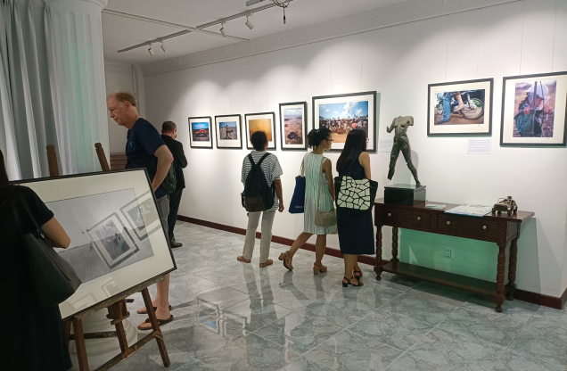 Visitors viewing photographs and sculptures in an art gallery.