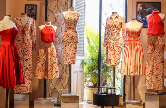 A display of fashionable red and patterned dresses in a boutique, showcasing various styles and designs.