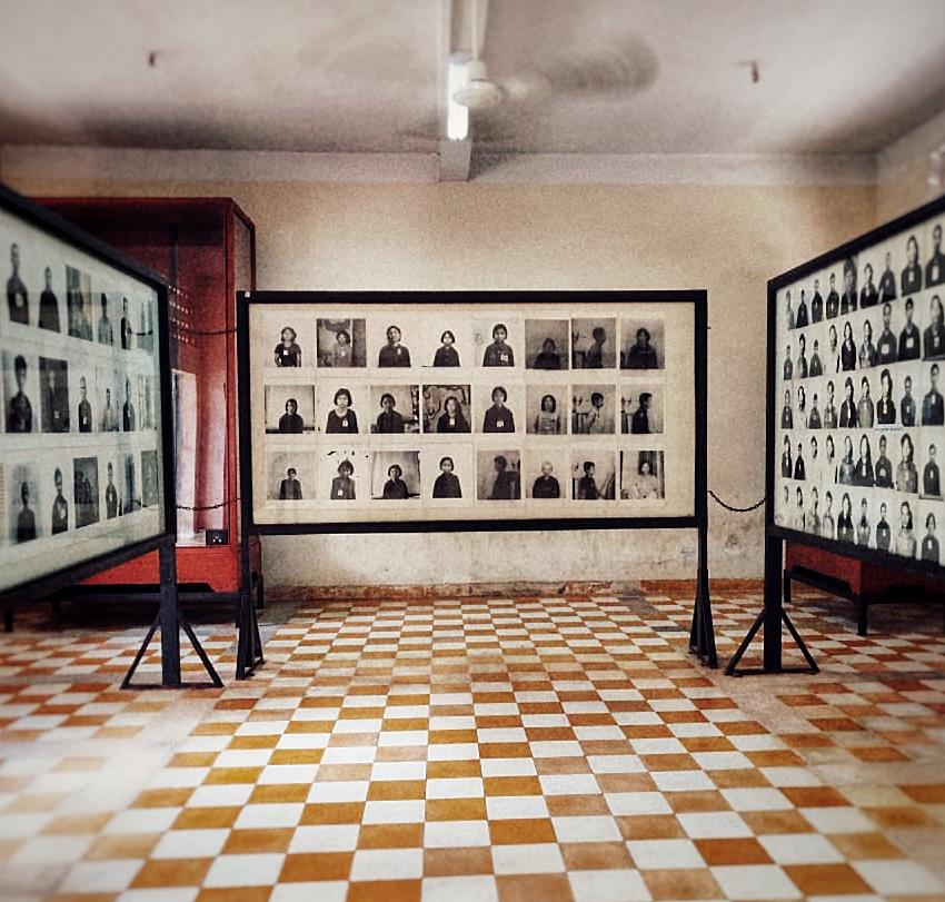 Interior of a museum with several large displays showcasing black and white portraits, possibly related to historical events, set against a patterned tiled floor.