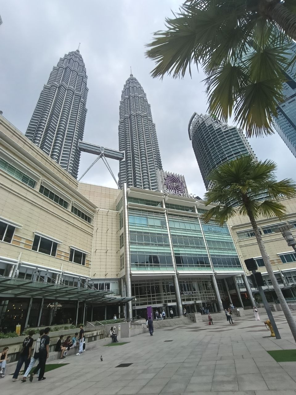 Suria KLCC exterior with the Petronas Twin Towers rising above and palm trees in the foreground