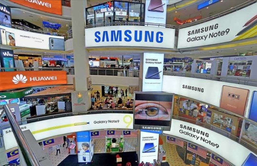 Interior of Plaza Low Yat shopping mall with Samsung and Huawei screens and multiple levels of electronics stores
