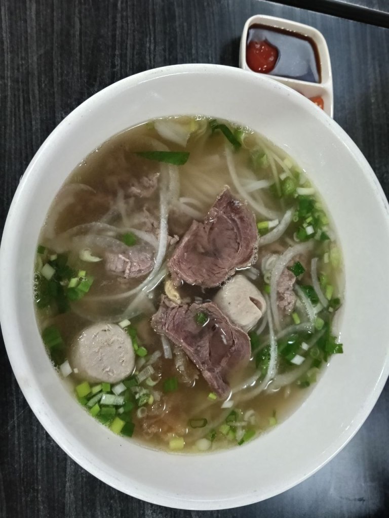 White bowl of pho with beef and meatballs at Vinh City