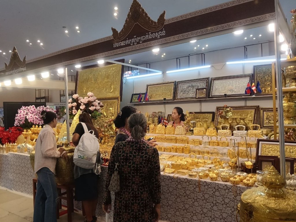  Visitors browsing a stall filled with traditional Khmer golden lacquerware, Buddhist decorative items and framed Khmer artwork at the Khmer Food Must Be Strong exhibition Koh Pich 2026