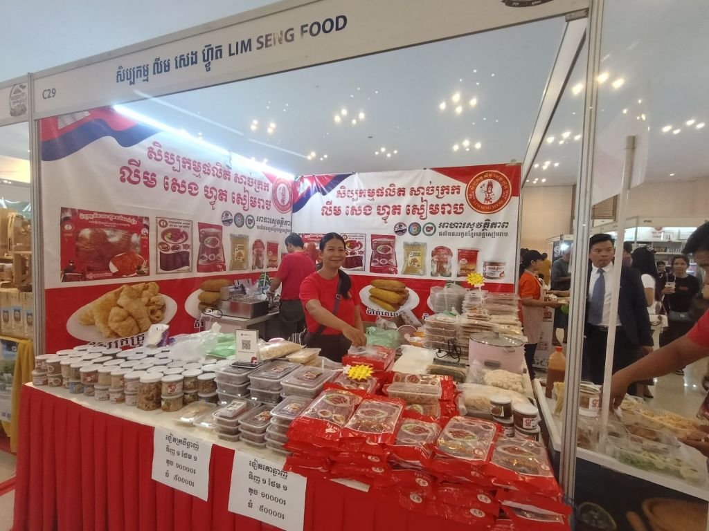  A vendor at the Lim Seng Food stall at the Khmer Food Must Be Strong exhibition, with rows of packaged Cambodian sauces, snacks and food products on display at Koh Pich Theater 2026