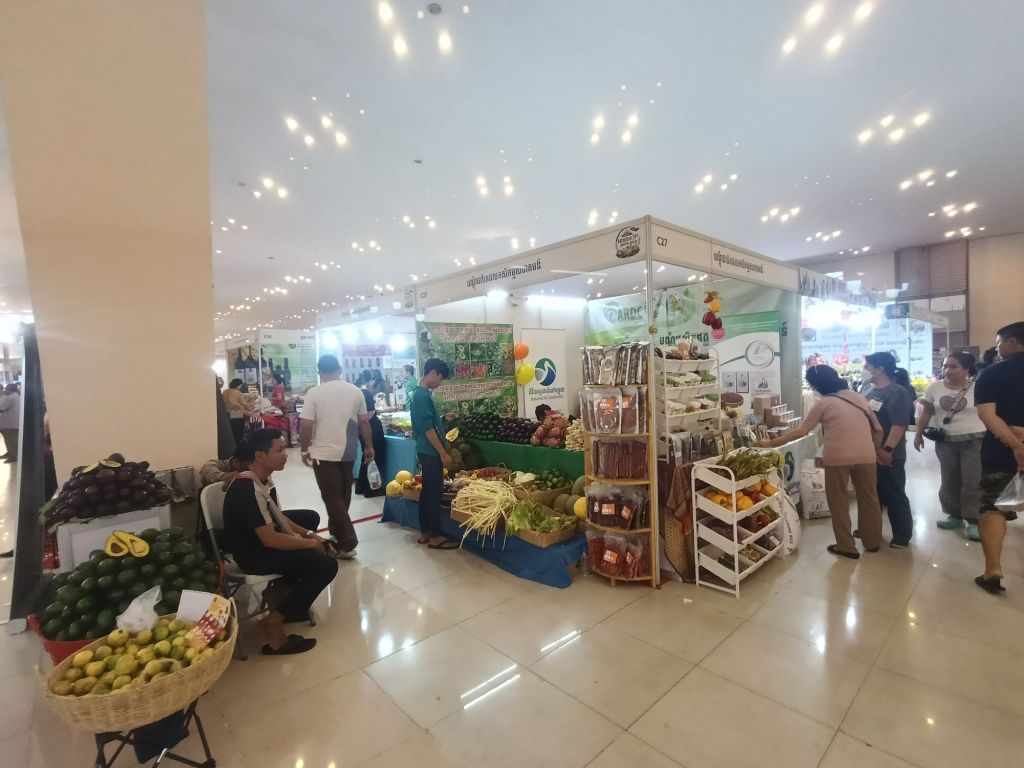 Vendors and visitors at Khmer Food Must Be Strong exhibition at Koh Pich Theater, with fresh fruits, vegetables and local Cambodia products on display.